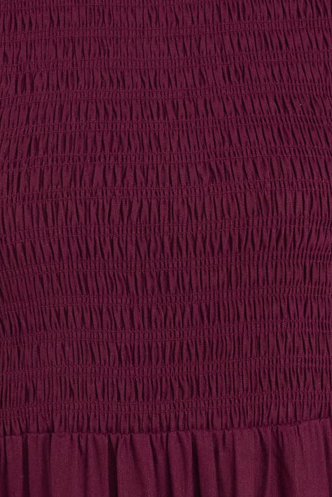 Woman wearing a burgundy dress with short sleeves against a white background