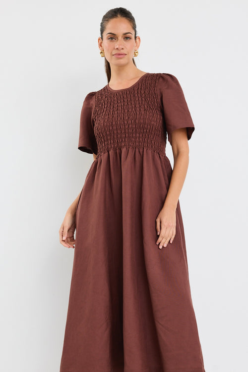 Model wears brown midi dress with a shirred cotton bodice and short sleeves