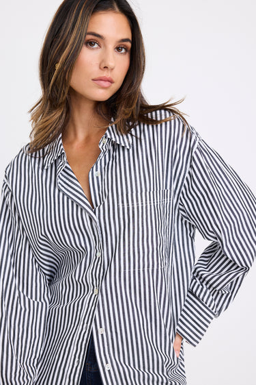 model wears a black and white stripe shirt with dark denim jeans