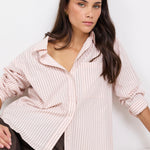 Woman wearing a light pink striped shirt and brown pants on a white background