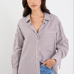 Woman wearing a striped shirt and blue jeans against a white background