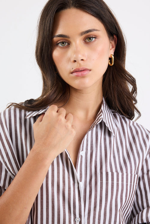 Woman wearing a black and white striped shirt against a plain background