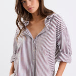Relaxed fit striped shirt with chocolate and white stripes, deep V-neck collar, and rolled-up sleeves, paired with ivory shorts.