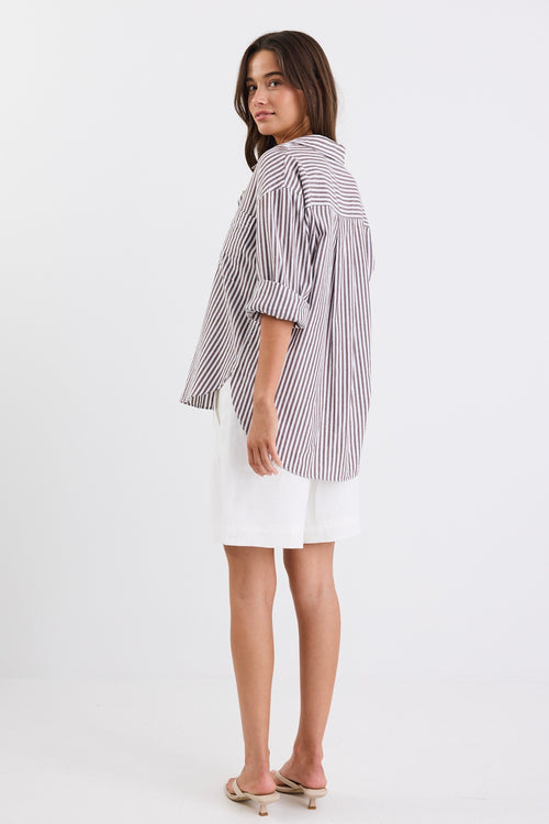 Relaxed fit striped shirt with chocolate and white stripes, deep V-neck collar, and rolled-up sleeves, paired with ivory shorts.
