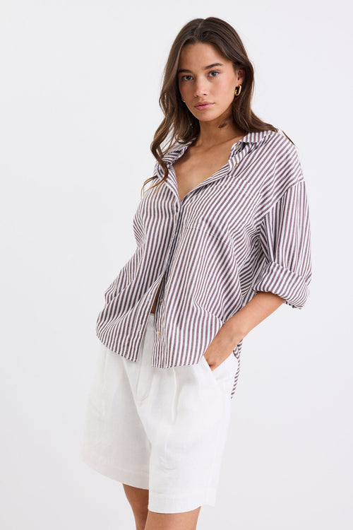 Relaxed fit striped shirt with chocolate and white stripes, deep V-neck collar, and rolled-up sleeves, paired with ivory shorts.