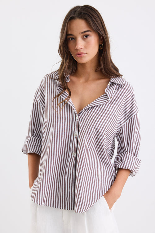 Relaxed fit striped shirt with chocolate and white stripes, deep V-neck collar, and rolled-up sleeves, paired with ivory shorts.