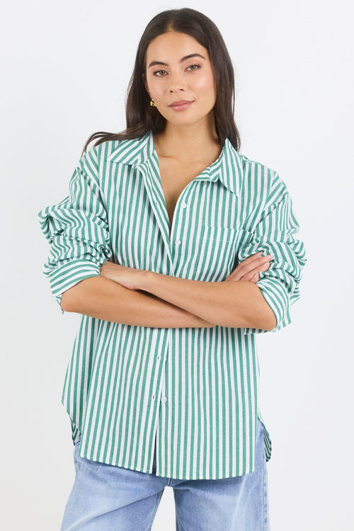 Woman wearing a green and white striped shirt with blue jeans on a white background