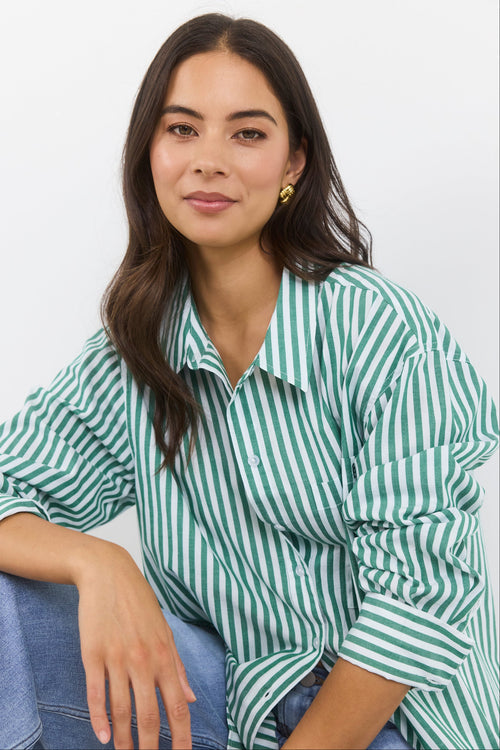 Woman wearing a green and white striped shirt against a plain background