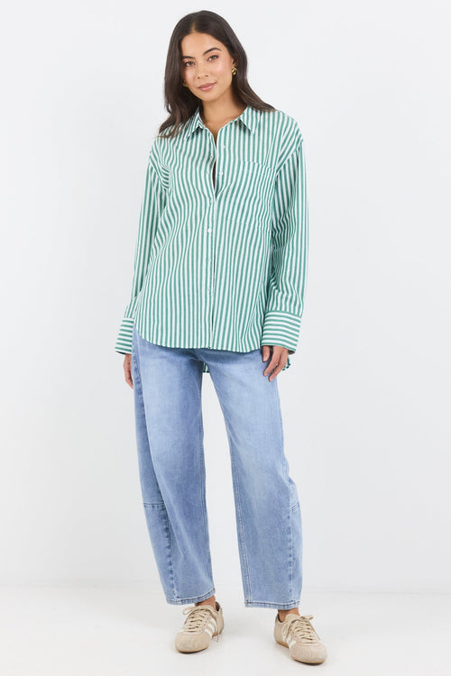 Woman wearing a green and white striped shirt and blue jeans on a white background