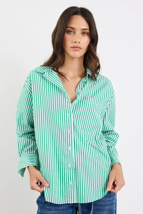 Woman wearing a green and white striped shirt with blue jeans on a white background