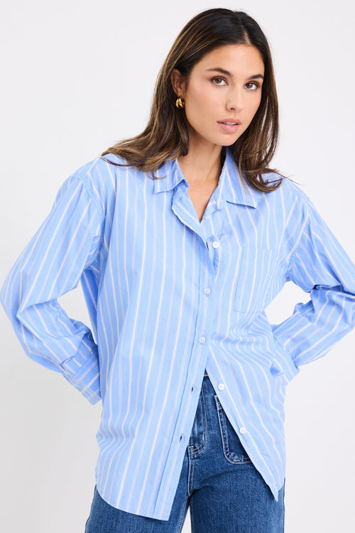 model wears a blue and white stripe shirt with dark blue jeans