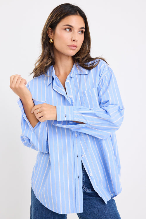 model wears a blue and white stripe shirt with dark blue jeans