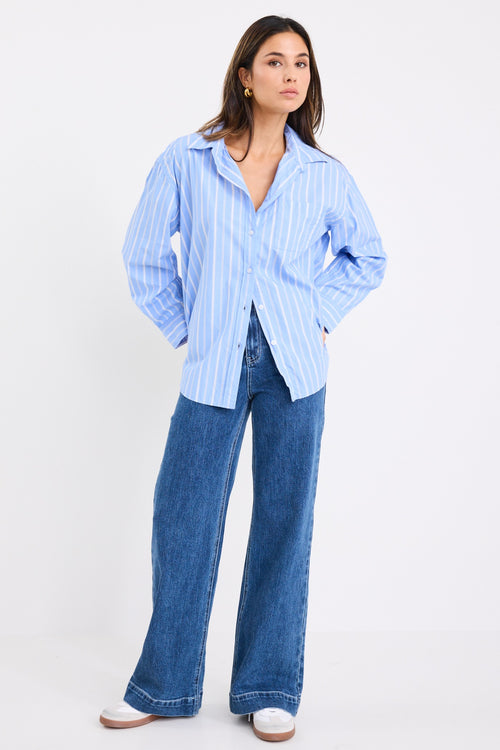 model wears a blue and white stripe shirt with dark blue jeans