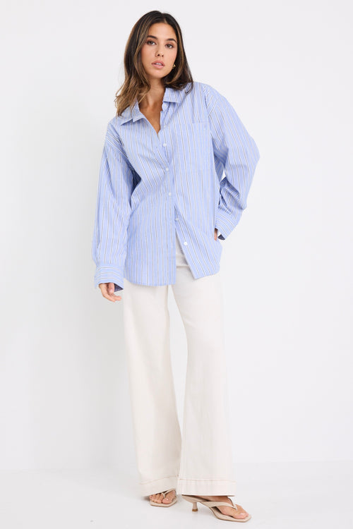 model wears a blue stripe shirt with ecru jeans