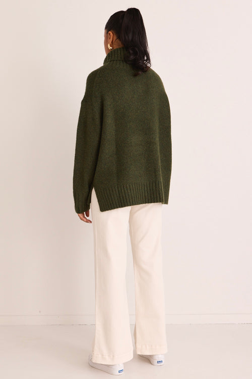 model wears a green turtle neck knit
