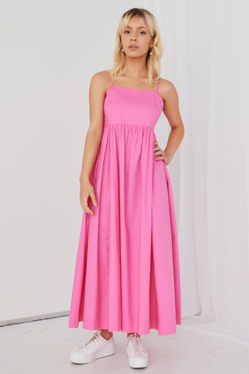 model posing in hot pink maxi dress and white sneakers