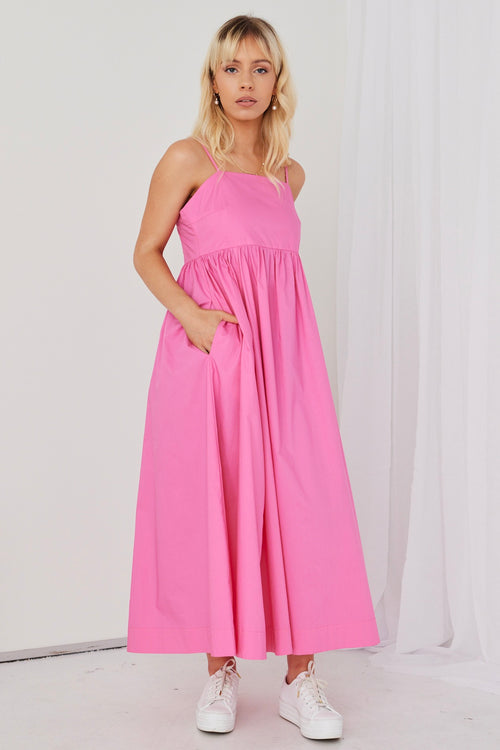 model posing in hot pink maxi dress and white sneakers
