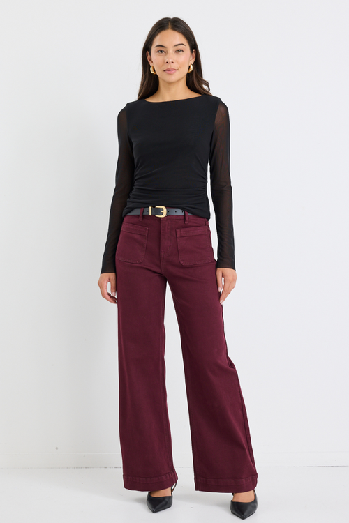 model wears red jeans with a black long sleeve top