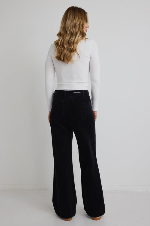 model wears white long sleeve top and black wide leg jeans with sneakers