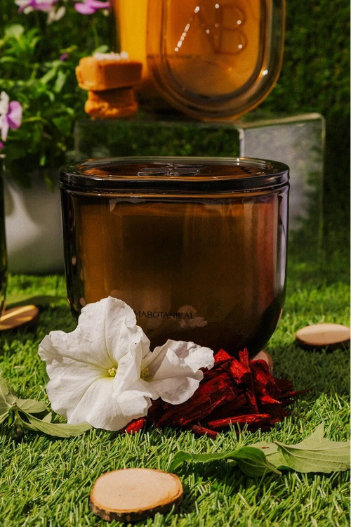 Candle with flowers and leaves on grass