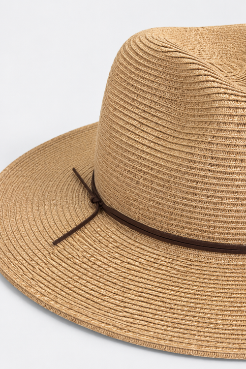 A close-up of a woven straw fedora hat in a natural tan color, featuring a dark brown ribbon band tied in a bow on the side, set against a clean white background.