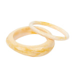 Two thick bangles with a marbled cream and yellow pattern, overlapping on a solid white background.