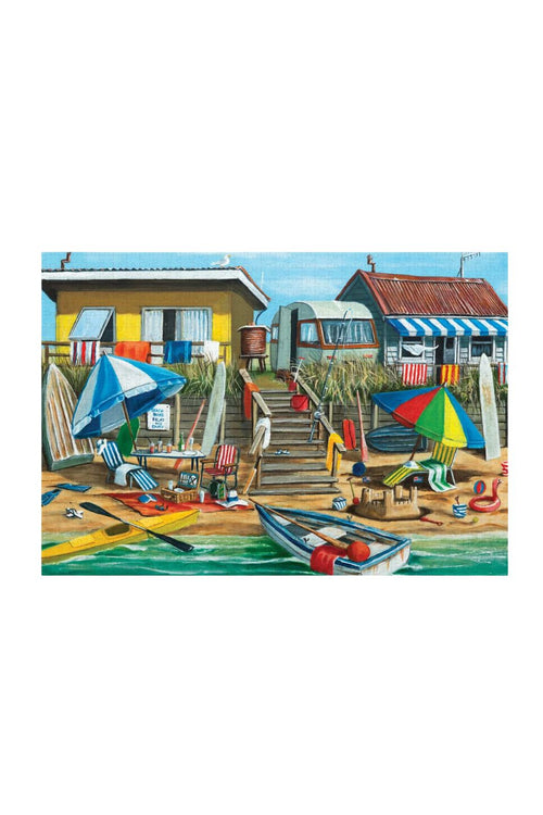 A colorful beachside scene artwork showing two small houses, stairs, umbrellas, beach chairs, a boat, and water, presented as a rectangular print centered on a white background.