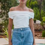 Woman wearing a mid-blue denim mini skirt with front panel pockets and an A-line shape.