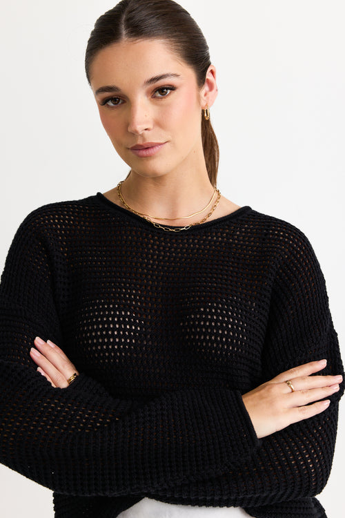 model wears a black knit top