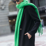 Model wears a black long coat with green scarf