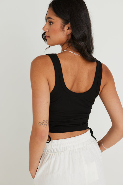 model wearing black crop tank top and white pants