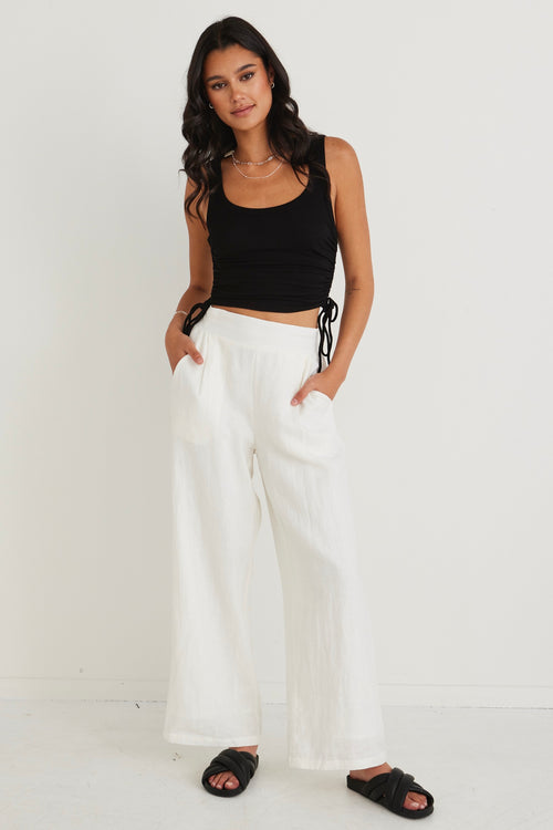 model wearing black crop tank top and white pants