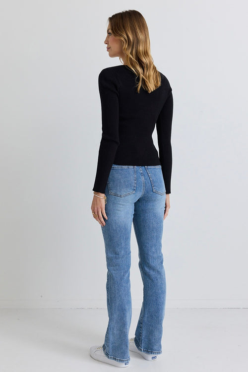 Model wears black knit top with jeans