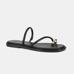 A single black leather flat sandal with a thin strap and a small gold metal ring detail on the toe post, shown against a light gray background.