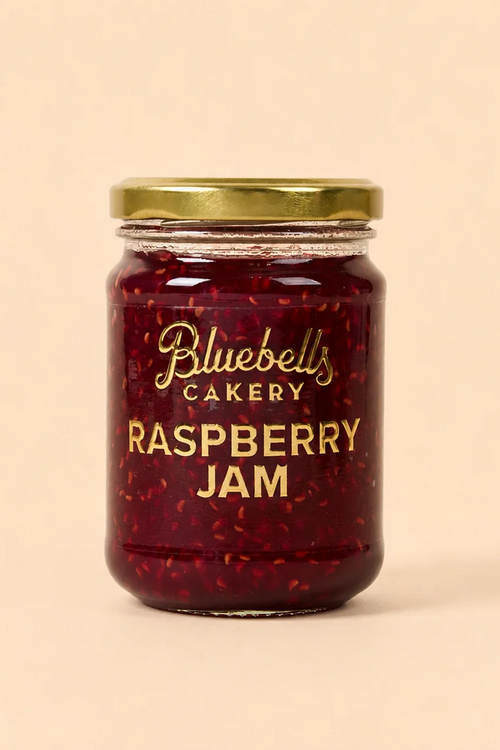 Bluebells Cakery Raspberry Jam in a glass jar with gold lid.