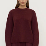 Person wearing a burgundy sweater and pants on a white background