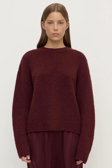 Person wearing a burgundy sweater and pants on a white background