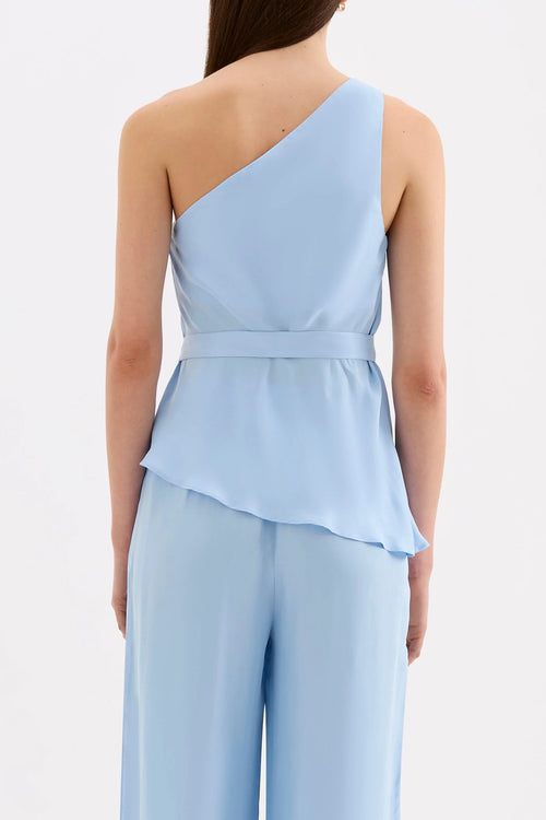 A model shown from the back wearing a light blue one-shoulder wrap top and matching wide-leg trousers against a plain white background.