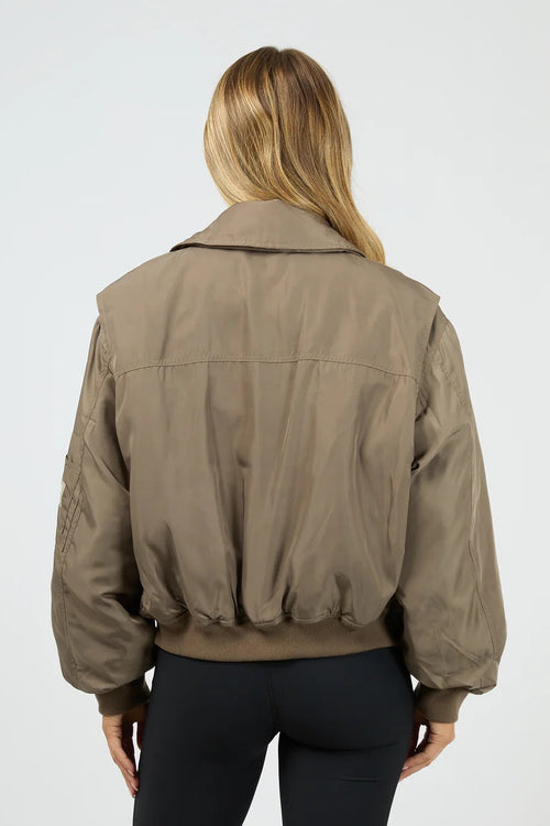 Person wearing a brown bomber jacket on a white background