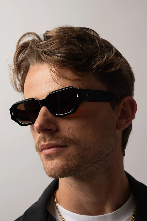 Man wearing black sunglasses with a neutral background
