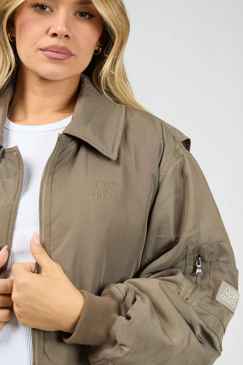Woman wearing a brown jacket with a brand logo on a white background
