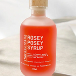 Bottle of 'Rosey Posey Syrup' on a light fabric background