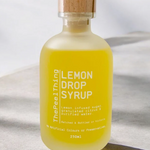 Bottle of lemon drop syrup with a wooden cap on a light fabric background
