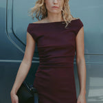 Woman in a burgundy dress standing next to a vehicle