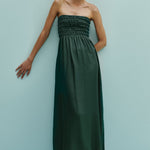 Woman wearing a strapless green dress against a light blue background