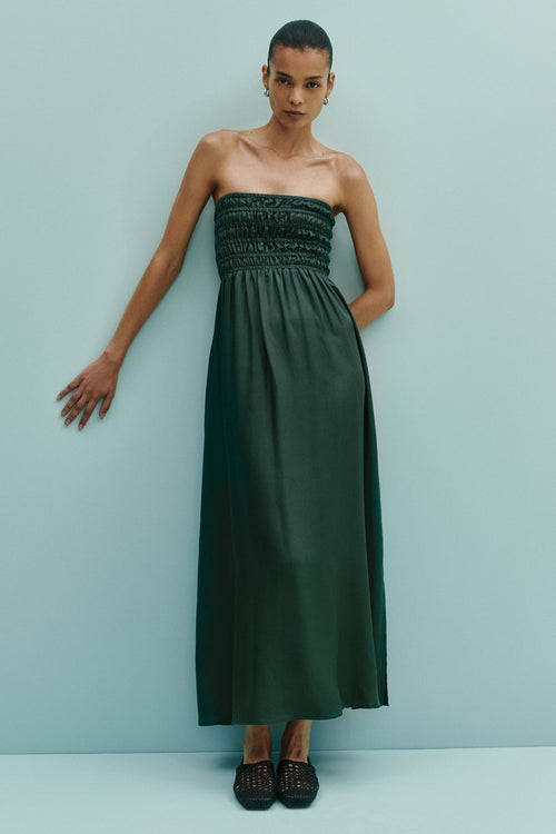 Woman wearing a strapless green dress against a light blue background