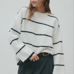 Woman wearing a white sweater with black stripes against a plain background