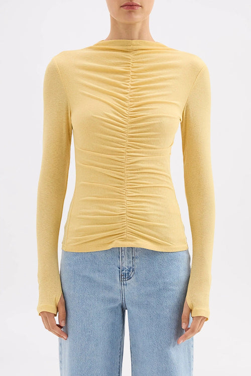 Yellow ruched long-sleeve top worn by a person on a white background