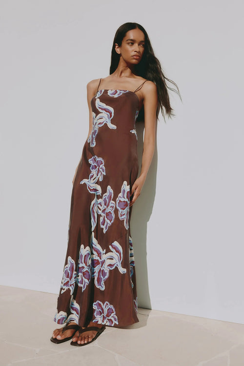 Brown floral maxi slip dress with thin straps, featuring a blue and cream abstract floral print and a straight neckline.