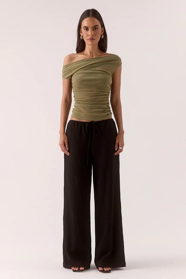 Woman wears a green ruched top and black pants
